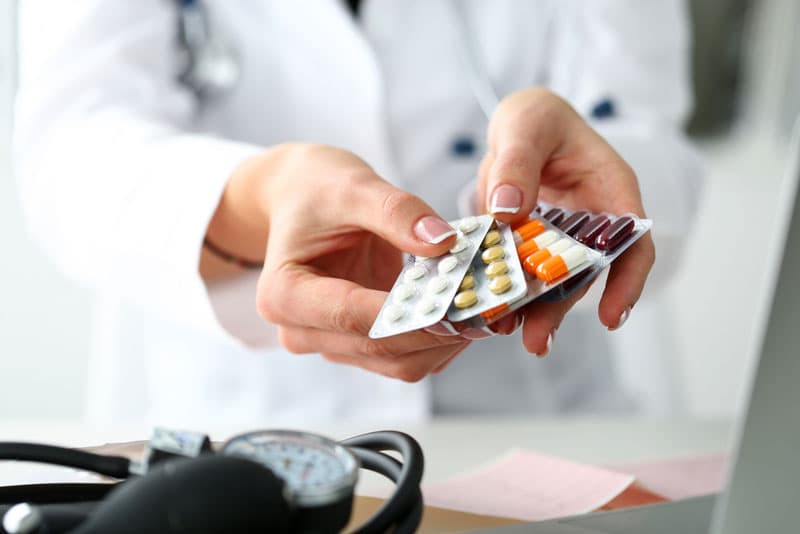 Eine Apothekerin hält verschiedene Blisterpackungen mit Medikamenten in der Hand.