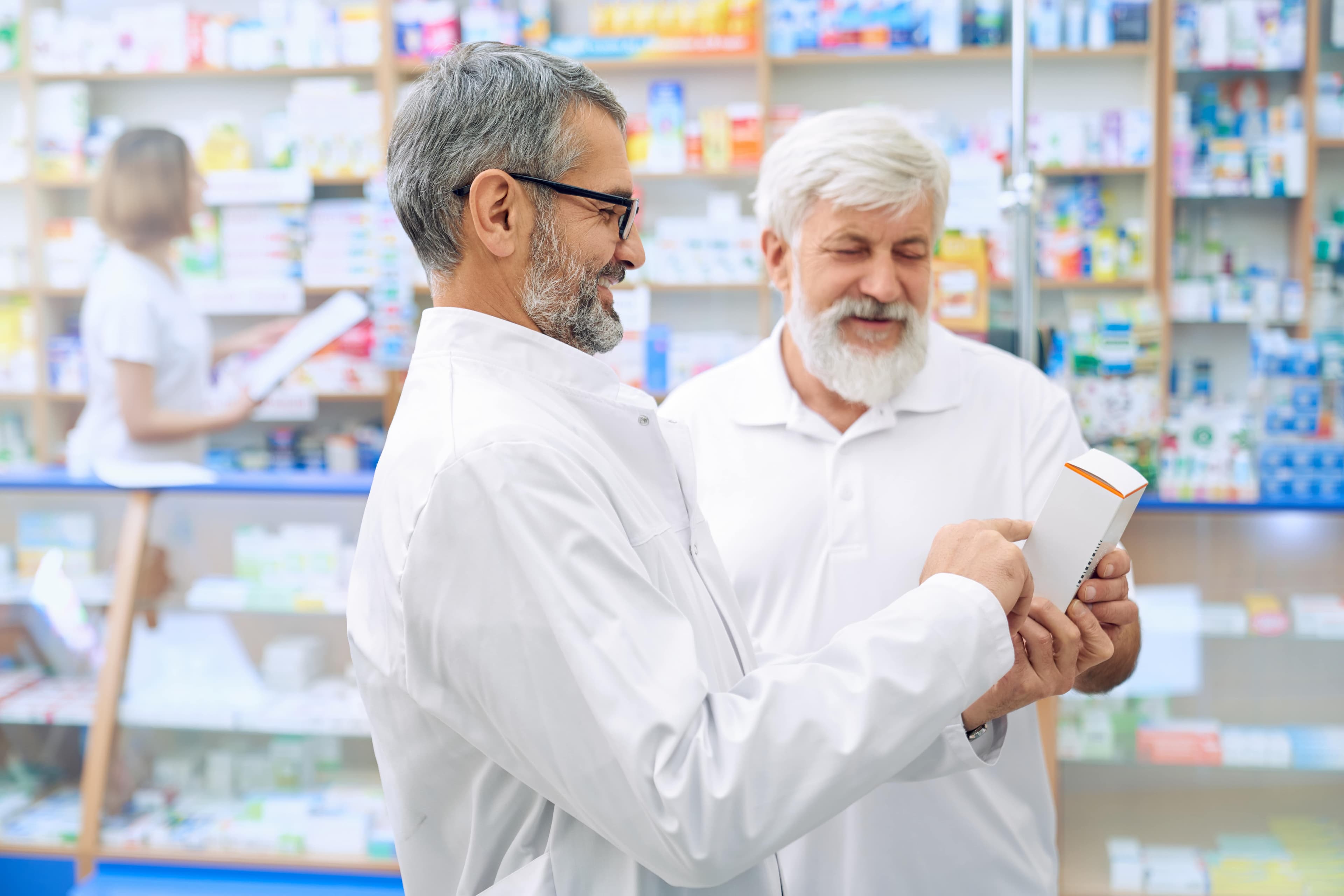 Ein Apotheker und ein Patient beraten sich in einer Apotheke über ein Medikament.